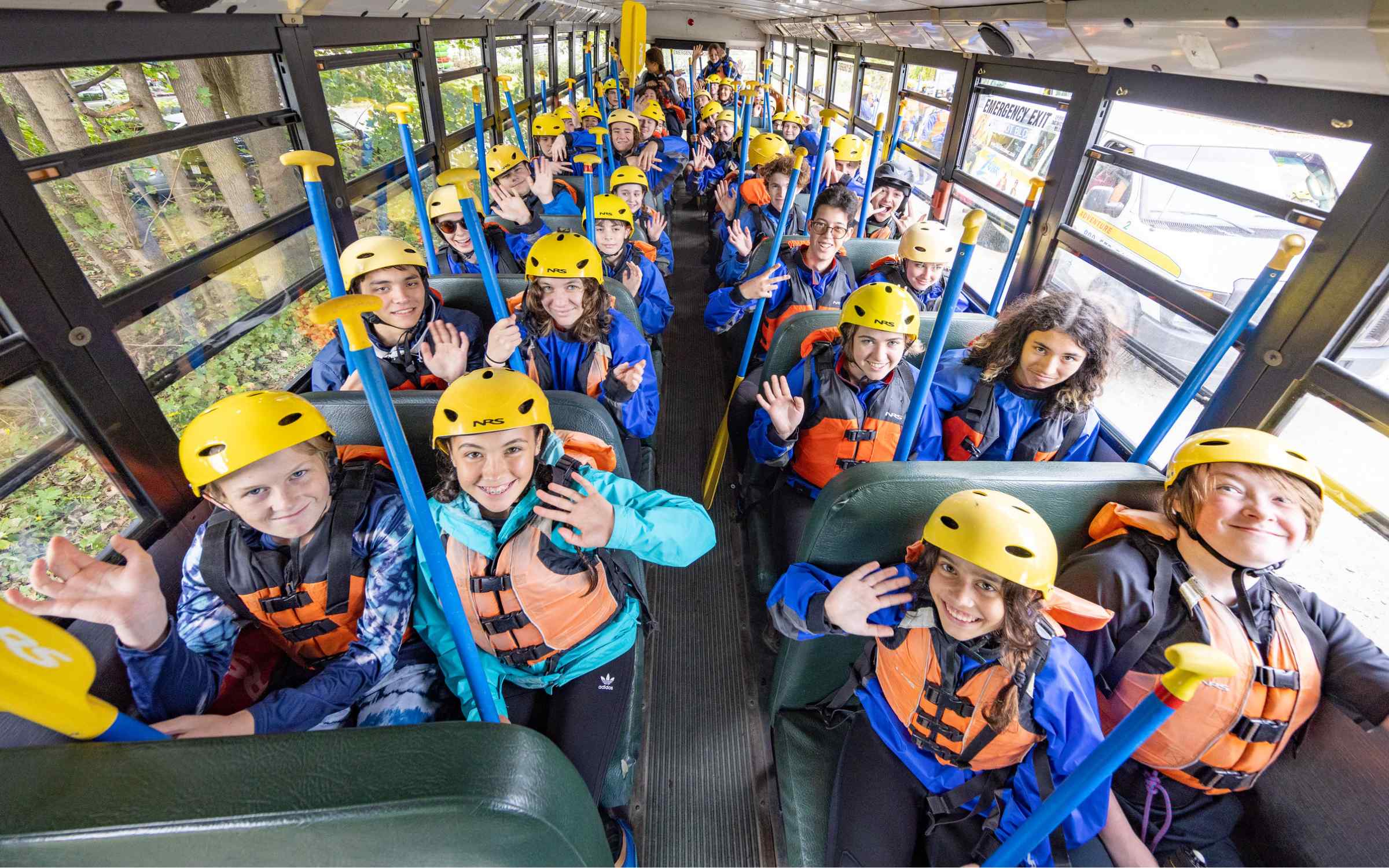 Excited school kids on bus ready for rafting adventure