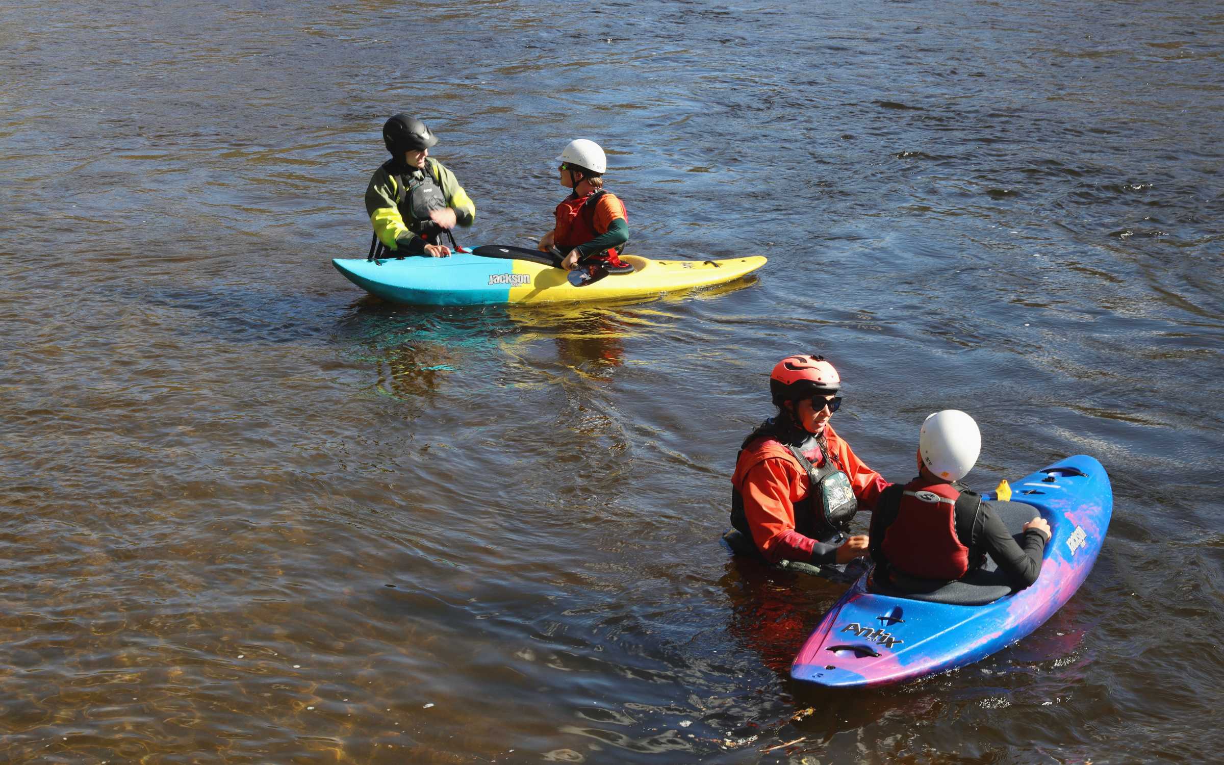 Two instructors in the water giving kayak lessons to two students
