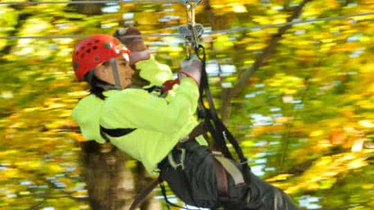 Woman zip lining through the trees