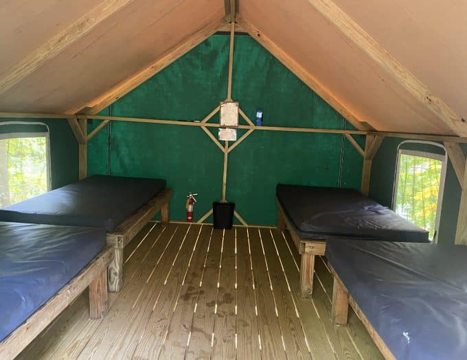 Inside of canvas cabin tent with four cots.