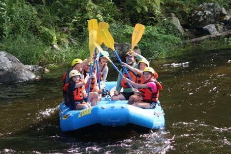 Smiling family enjoy a river rafting trip with Zoar Outdoor