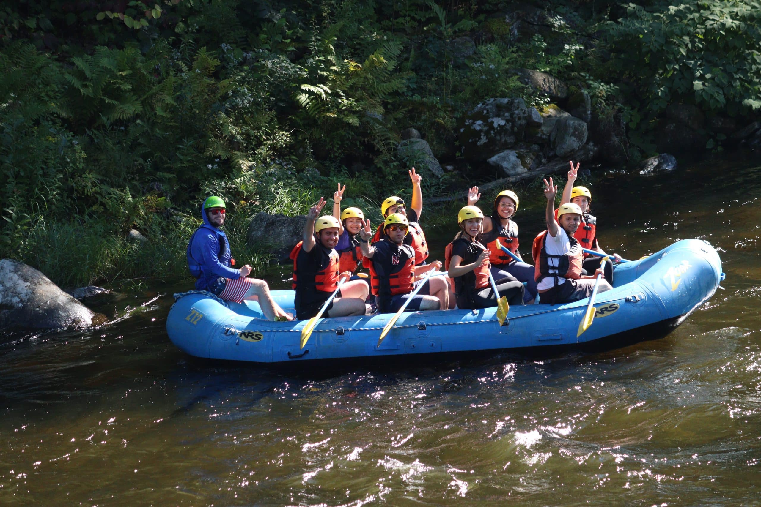 Zoar rafters waving to the camera on a peaceful section of the Deerfield River