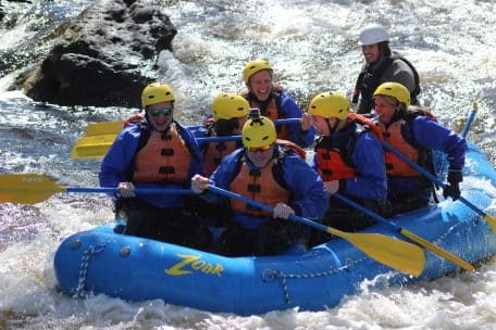 Laughing group of co-workers headed through whitewater rapids on the Zoar Gap trip