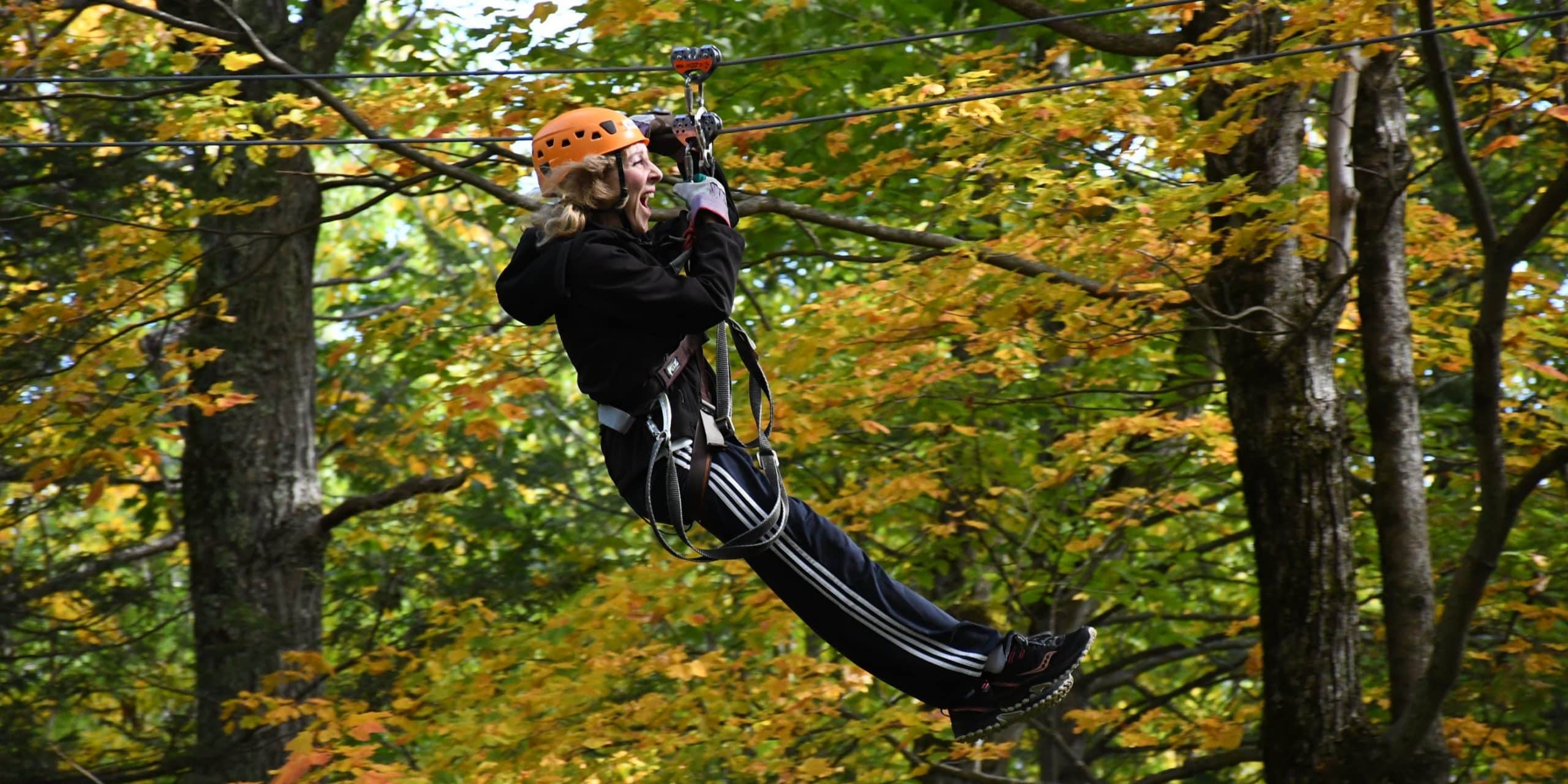 Young zipliner laughing & smiling while flying through the trees on Zoar's Zip Line Canopy tour