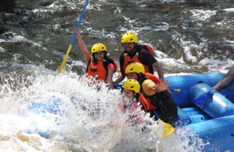 Group of people in a raft getting splashed by the rapids