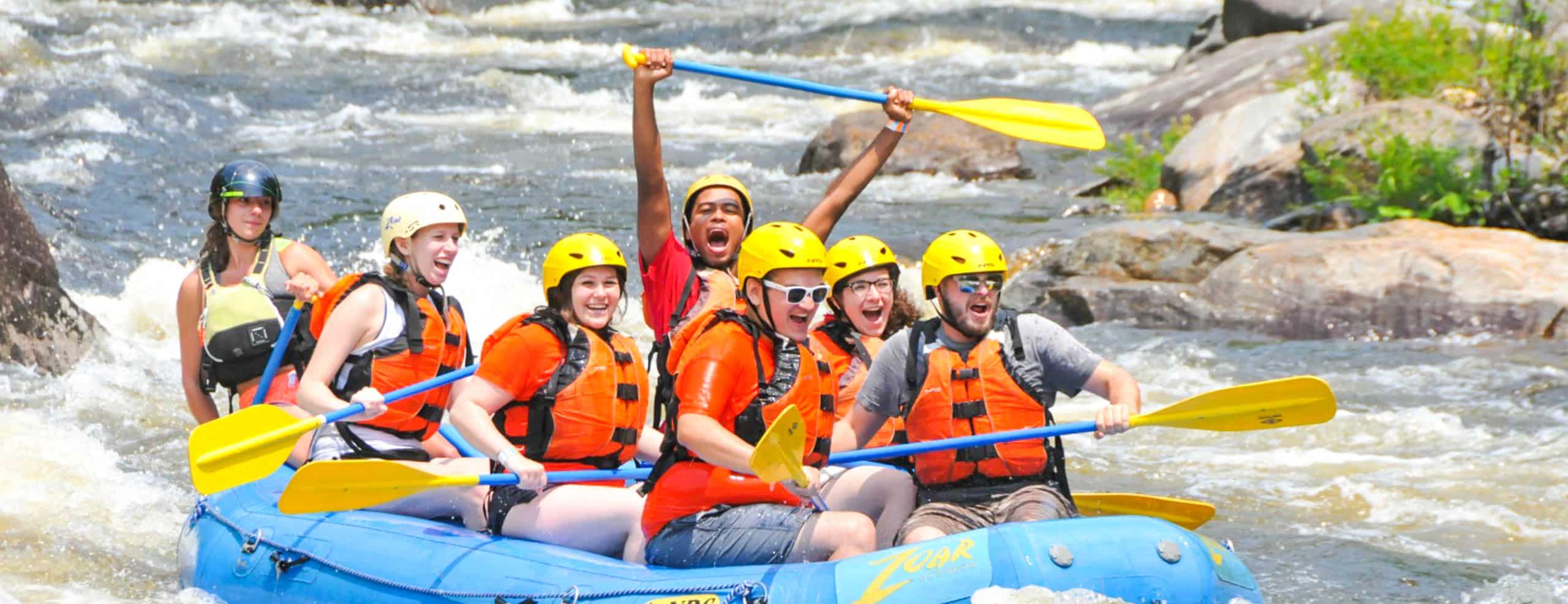 Group of people excitedly rafting on the river at Zoar Outdoor