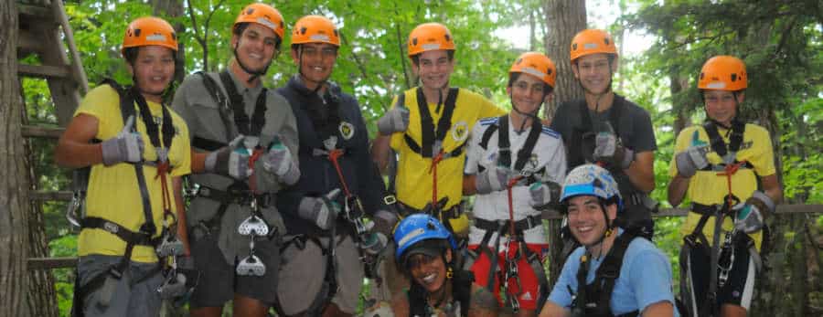 Group of boys and girl with zip lining helmet and harnesses ready to zipline