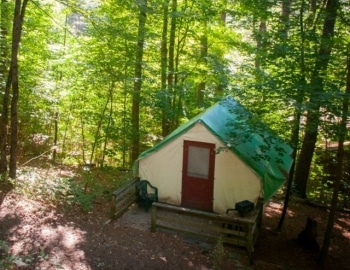 Cabin tent in the woods with porch and two chairs