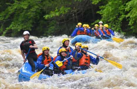 Group rafting down through whitewater rapids on the Miller River
