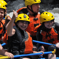 Boy giving a thumbs up as he rafts down the river