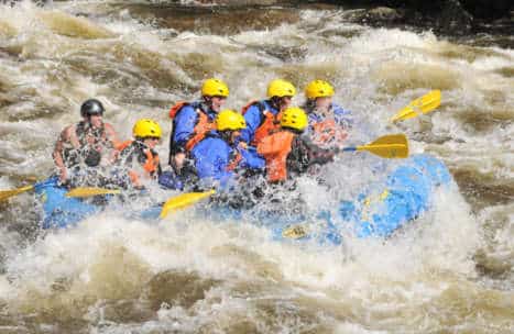 Group of rafters getting splashed and soaked by water from rapids