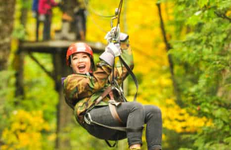 Young woman smiling as she ziplines through the forest