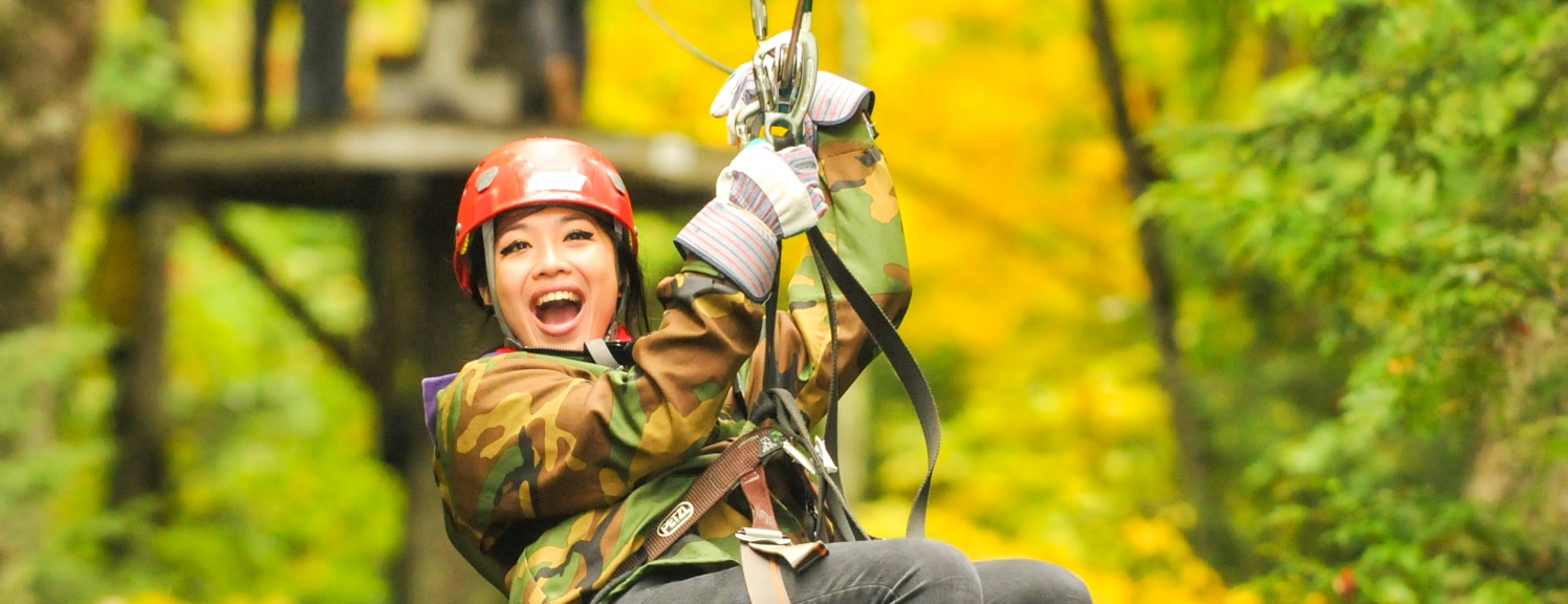 Young woman smiling as she ziplines through the forest