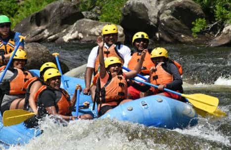 Group of people in a raft having fun and smiling during small rapids