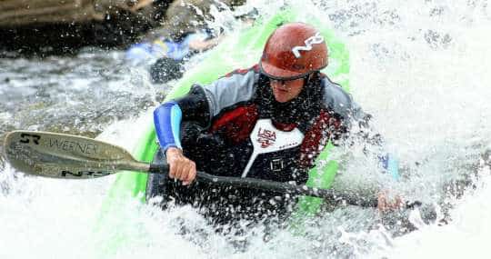 Kayaker paddling through a whitewater rapid on the Deerfield River, wearing an NRS helmet