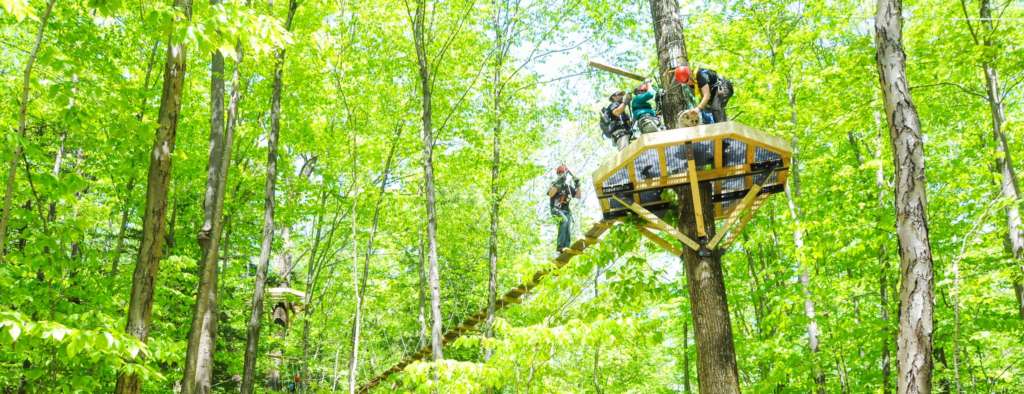 Group of people on a zip line platform high in a tree at Zoar Outdoor
