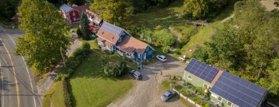 aerial view of farmhouse and a green building with solar panels