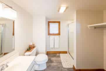 Bright white large bathroom with toilet, sink, bath shower, and closet