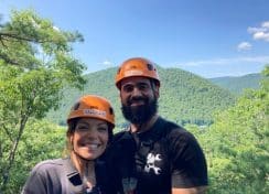 couple ziplining with a view of rolling mountains