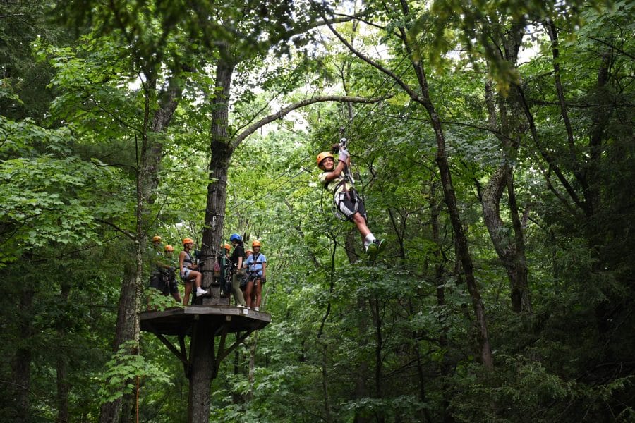 child zip lining down from a platform in the forest