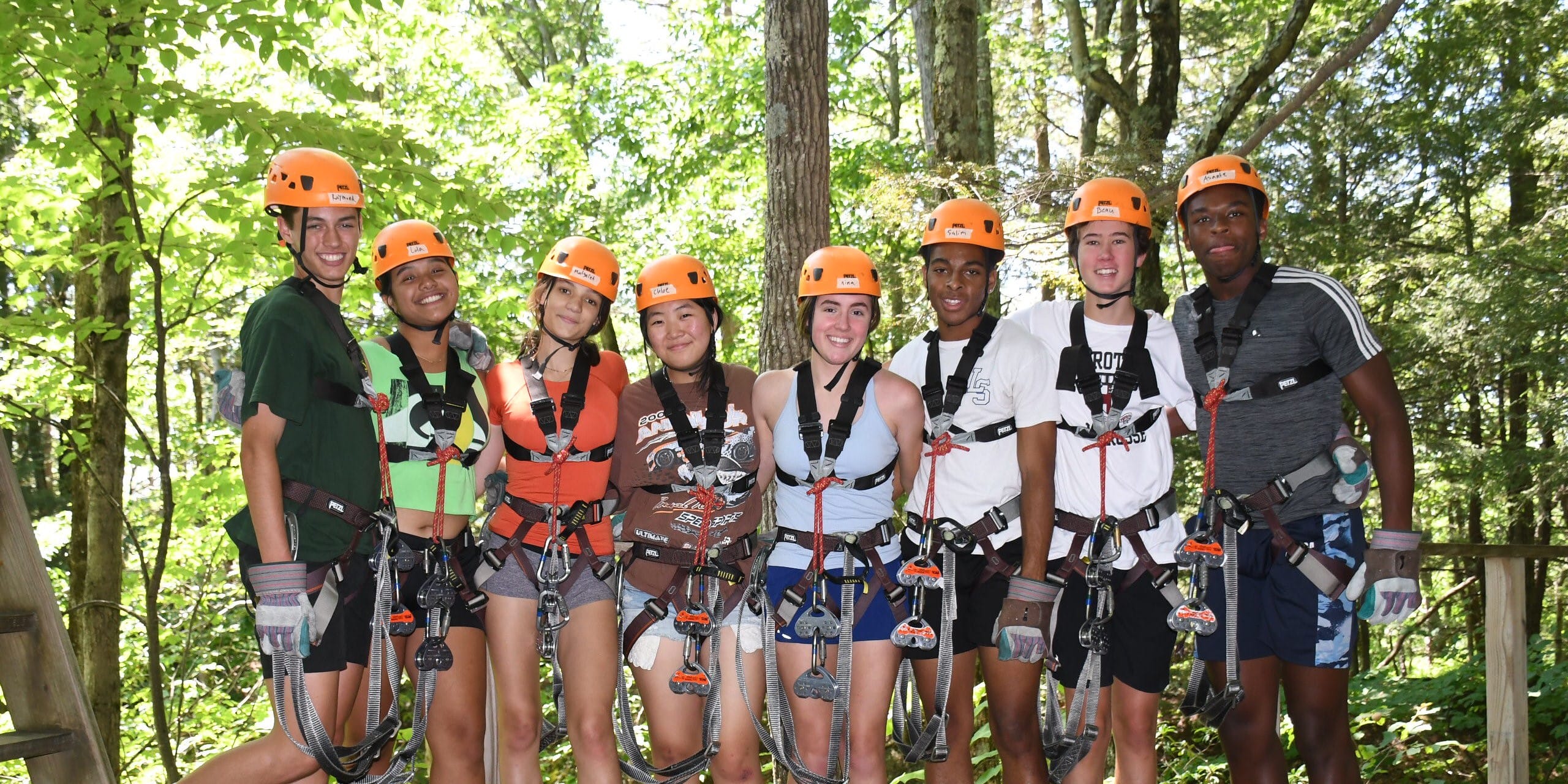 group of high school students in zipline gear smiling on zipline platform