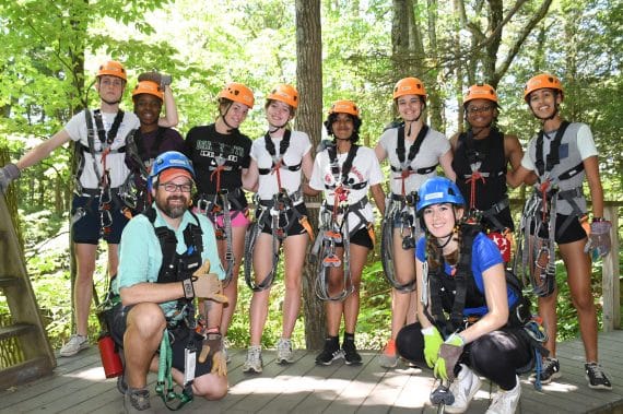 group of young people with two guides posing on a zipline platform