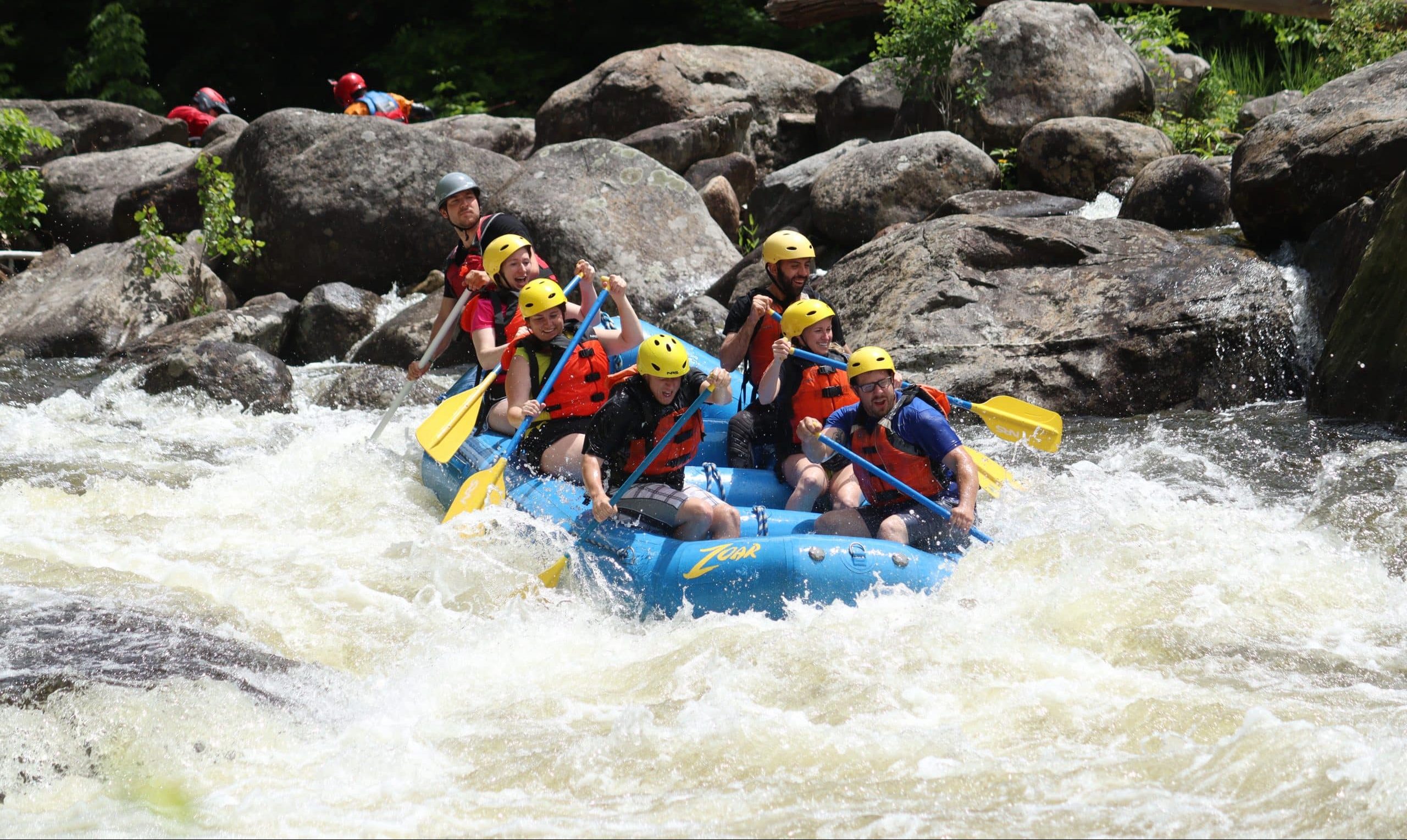 Smiling rafters headed into whitewater on a sunny day on the Deerfield River